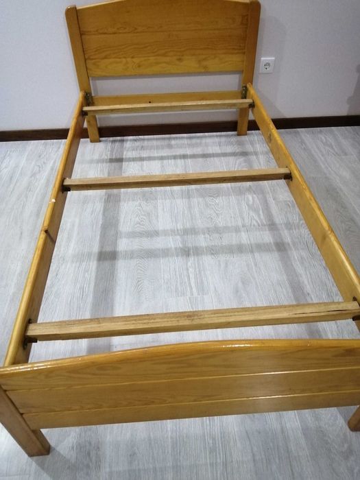 Cama de solteiro com mesinha de cabeceira.