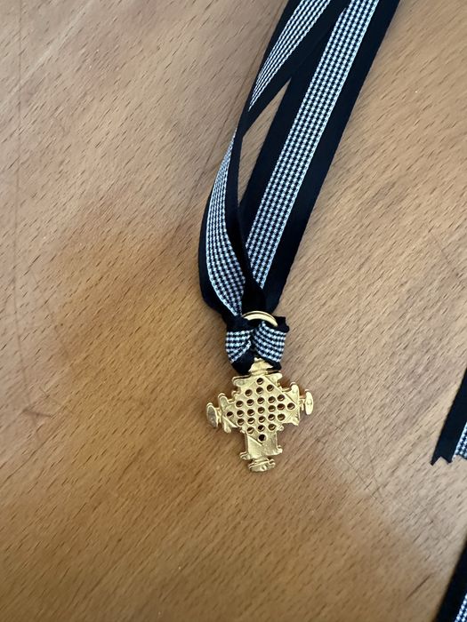 Cruz dourada com fita em seda