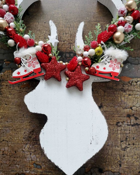 Drewniana głowa renifera z ozdobami i zielonymi gałązkami święta