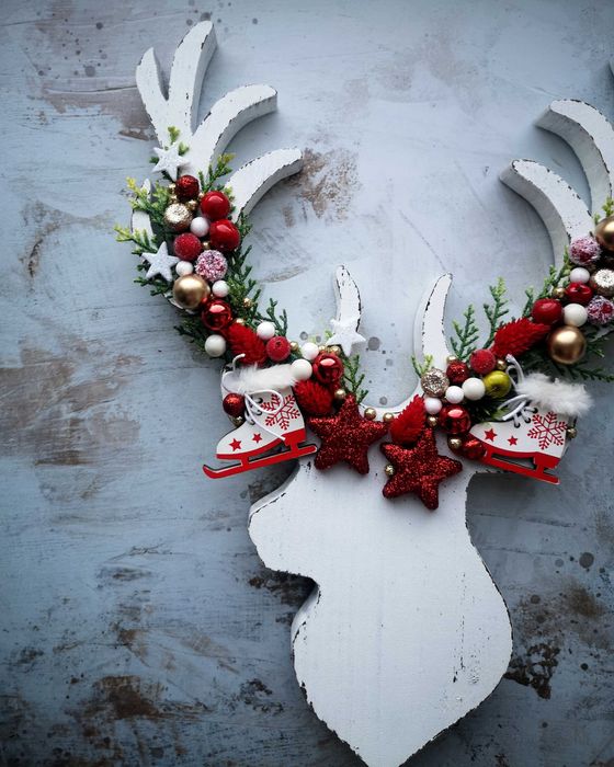 Drewniana głowa renifera z ozdobami i zielonymi gałązkami święta