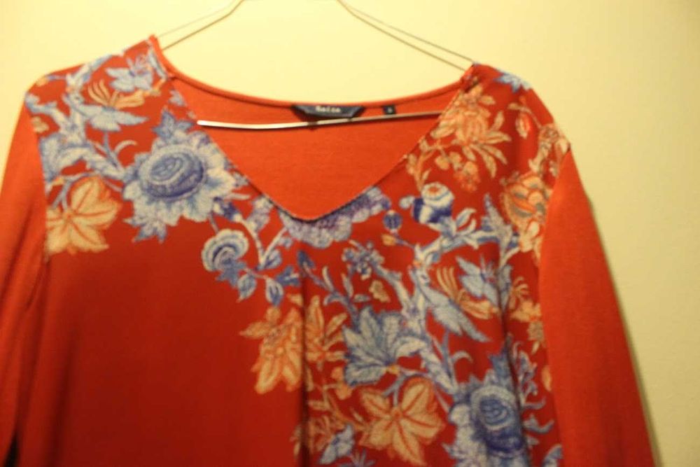 Blusa romântica com motivos florais azuis em fundo vermelho