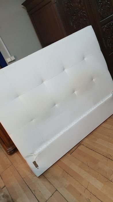 Cama estofada e mesinhas com marcas de uso estrado