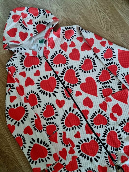 Casaco comprido com corações vermelhos em fundo branco.  TU