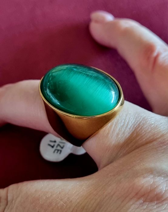 Anel dourado, em aço, com grande pedra verde oval. T17