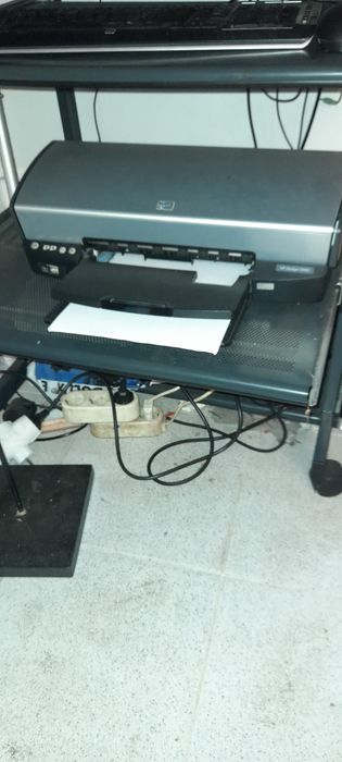 Computador HP, impressora, sistema de som e secretária.