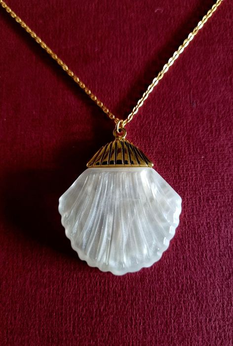 Colar dourado, em aço, com concha em madrepérola.  Tem extensor.