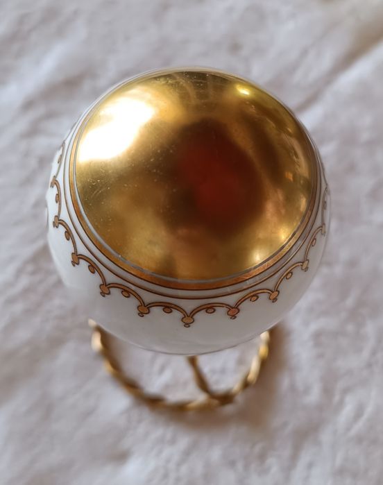 Ovo de Páscoa de porcelana com decorações douradas.Assente num suporte