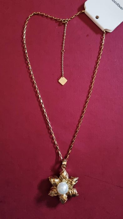 Colar dourado, em aço, flor com pérola. Tem extensor