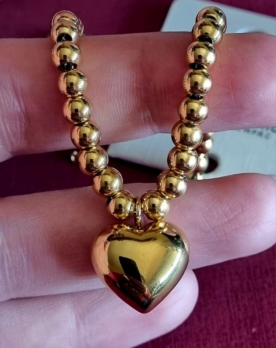 Pulseira dourada, em aço, toda às bolinhas e com 1 coração. Tem extens