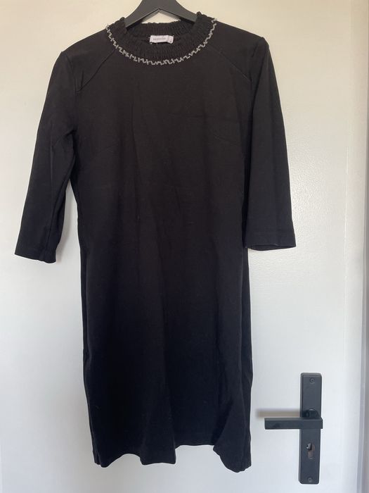 Dzianinowa sukienka z ozdobą przy dekolcie.