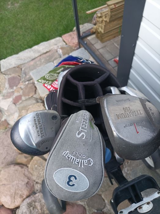 Zestaw kijów golfowych wraz z torbą i wózkiem.