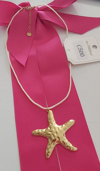 Colar dourado, em aço, com pingente em forma de estrela. Tem extensor