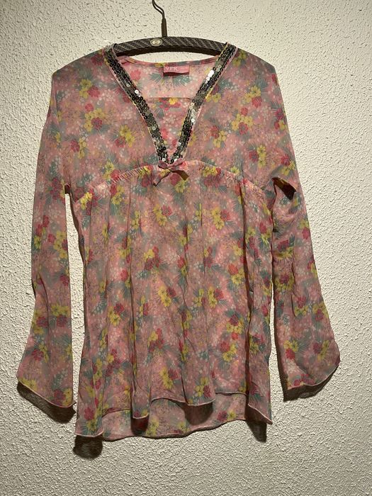 Różowa bluzka z kwiatowym nadrukiem i cekinami.