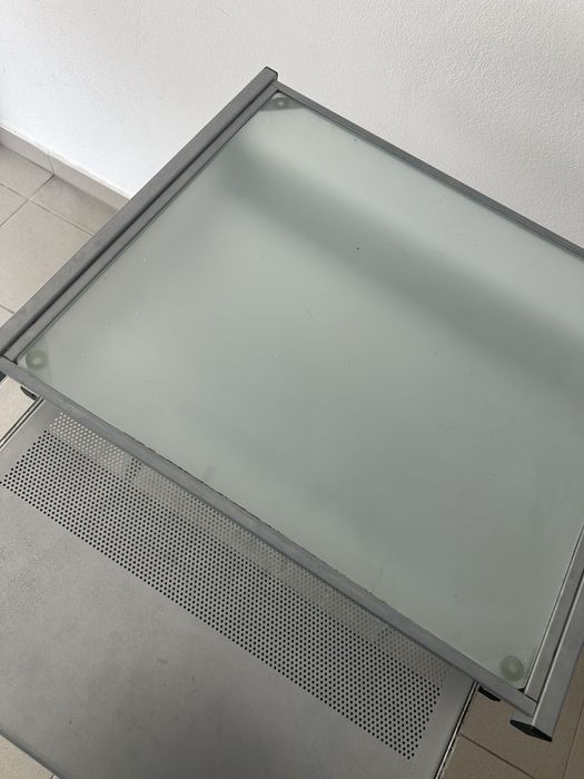 Secretária de computador compacta em metal e vidro.