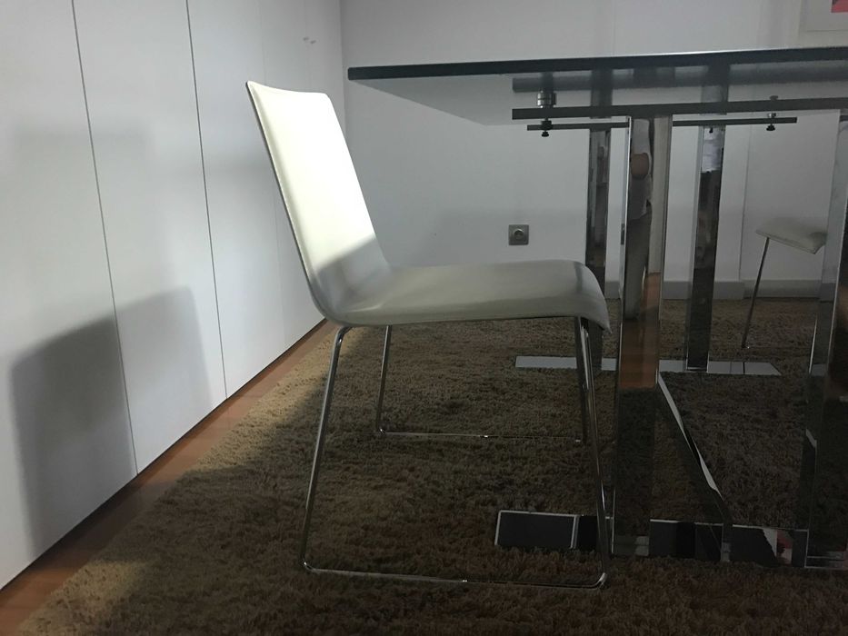 quatro cadeiras de pele branca e base em inox