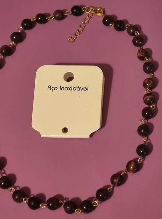 Colar dourado, em aço, às bolinhas castanhas de pedra natural "olho de gato". Tem extensor.
