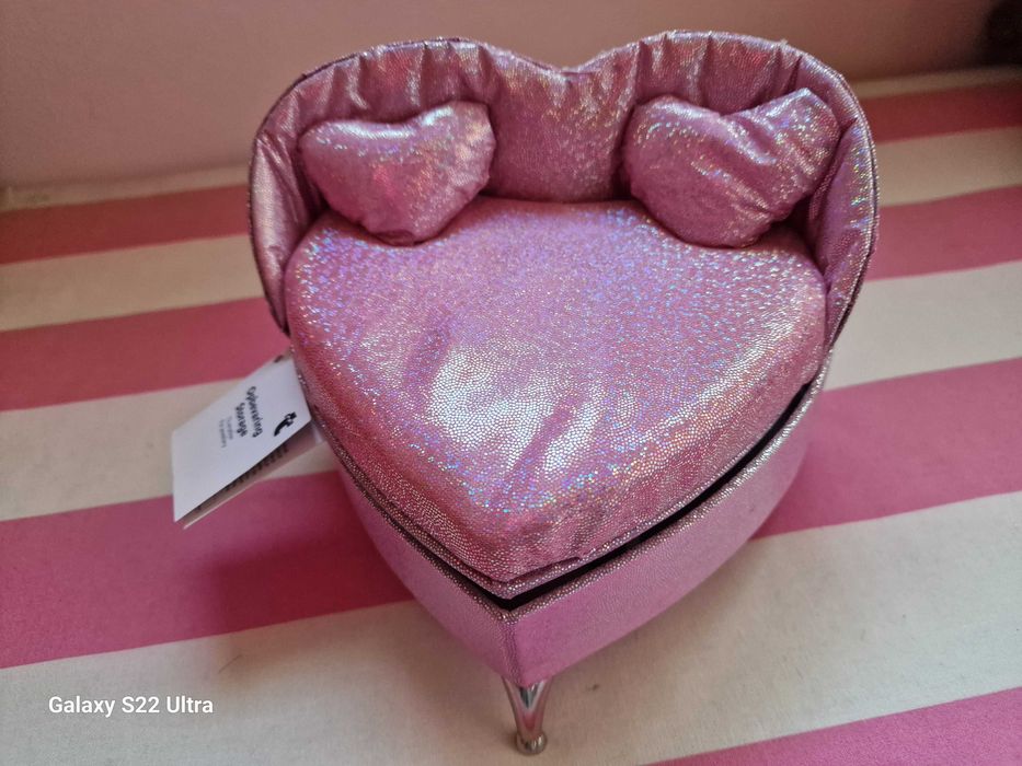 Pequena caixa de joias em forma de cama, de cor rosa.