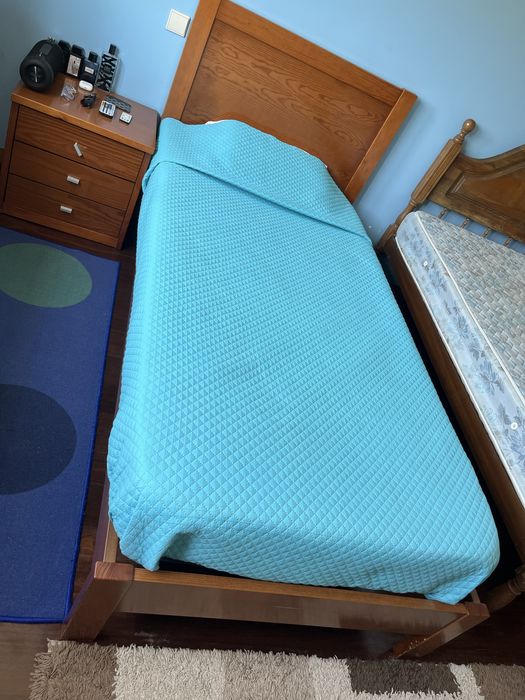 Cama solteiro com 2m de cumprimento e 1m de largura, com colchão e mesinha de cabeceira.