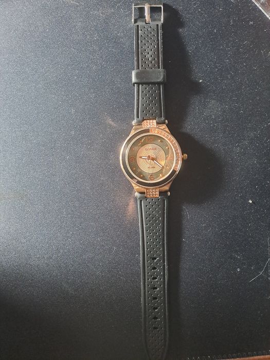 Relógio dourado e preto com pedrinhas