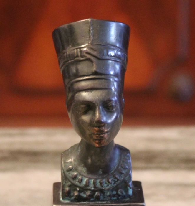 Busto de Nefertiti com 15,5cm de altura em metal sobre madeira.