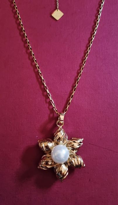 Colar dourado, em aço, flor com pérola. Tem extensor