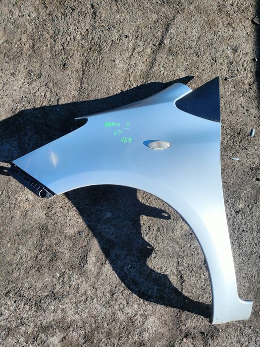 Toyota Yaris 2 II błotnik lewy przód srebrny 1E7