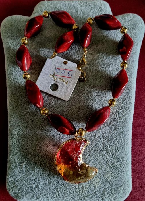 Colar dourado, em aço, com peças bordeaux em acrílico e uma meia lua.