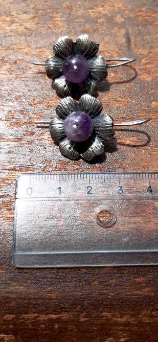 Brincos prateados em forma de flor com pedra roxa