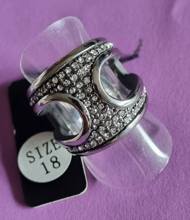 Anel prateado, em aço, aberto dos lados e cheio de zirconias. T17/18