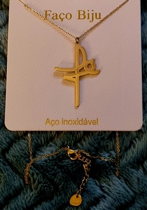 Colar dourado, em aço, a dizer " fé". Tem extensor
