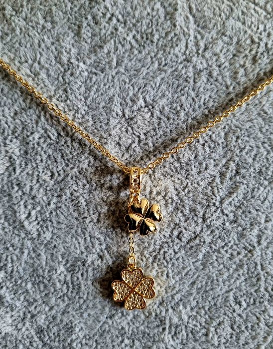 Colar dourado, em aço, com 2 trevos pendentes. Formato gravata.