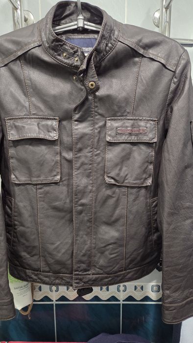 мужская коричневая кожаная куртка с карманами на груди и рукавах.