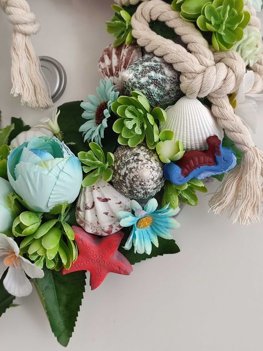 Guirlanda artesanal marítima com flores, conchas e farol decorativo