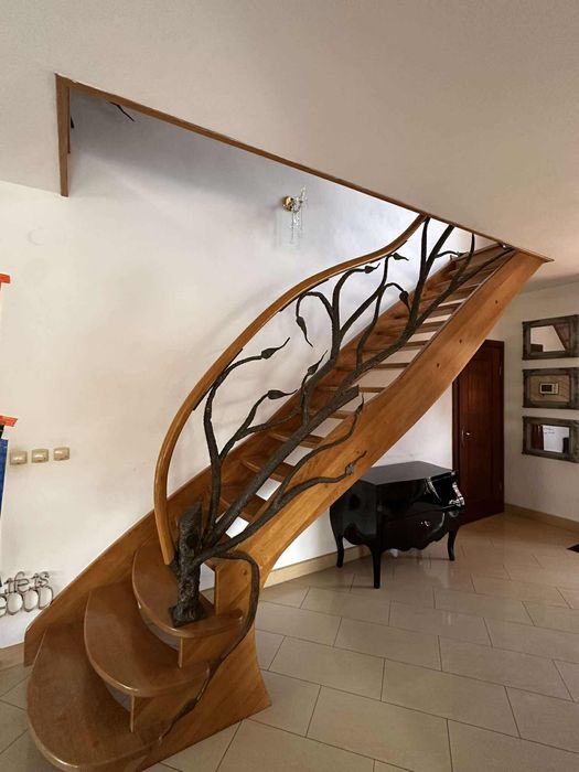 Piękne dębowe schody z kuta barierka i giętą poręczą