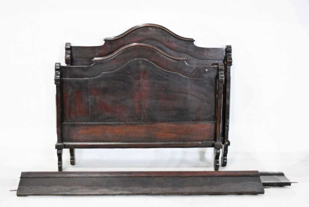 Cama em madeira com cabeceira e traseira com parte superior recortada.