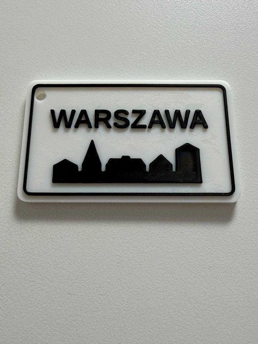 Brelok Warszawa w formie znaku drogowego.