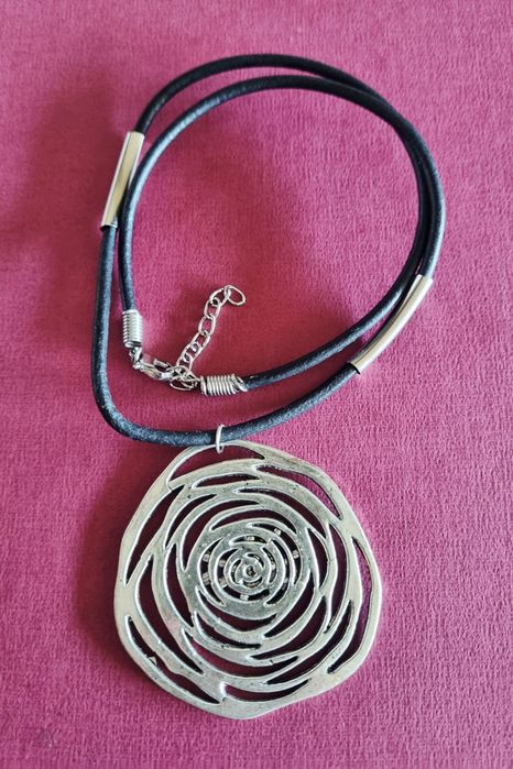 Colar preto com flor em prateado. Tem extensor