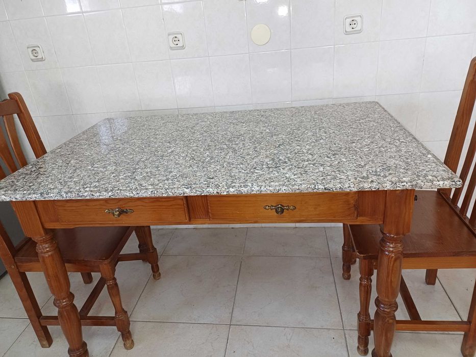 Mesa de cozinha com tampo em granito polido e quatro cadeiras.
