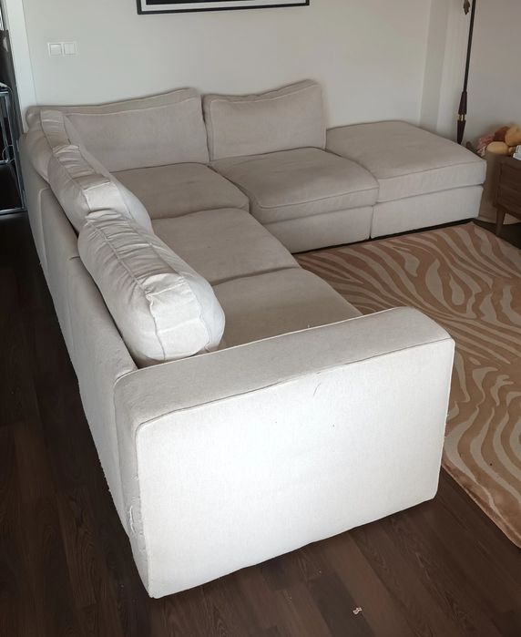 Sofá de canto bege, gato preto