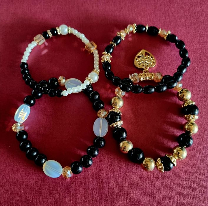 Conjunto de 4 pulseiras elásticas em tons de preto e dourado.