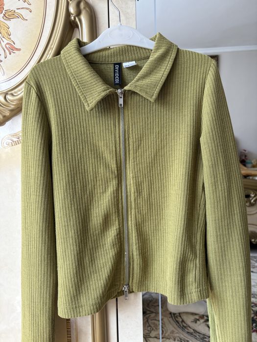 зелений лонгслів у рубчик з коміром та блискавкою від бренду H&M.