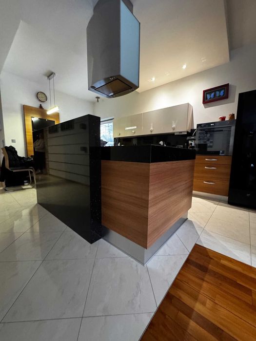 Kuchenna wyspa z zabudową meblową i granitowym murkiem.