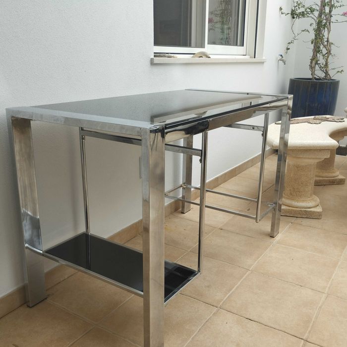 Mesa de escritório em vidro e cromo. Dimensões: comprimento 120 cm, largura 60 cm, altura 76 cm.