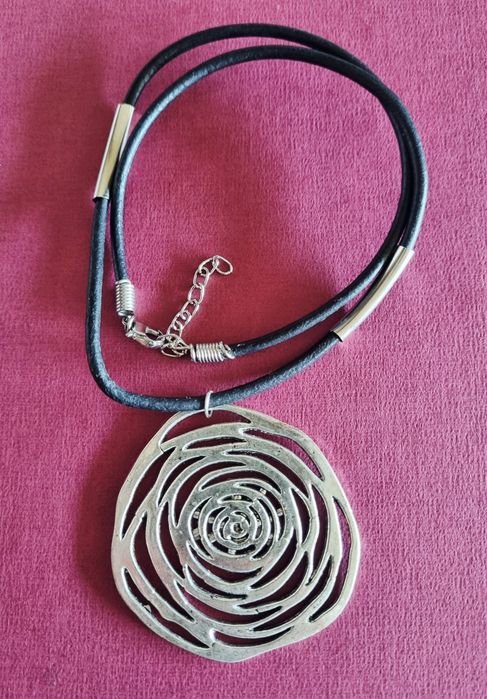 Colar preto com flor em prateado. Tem extensor