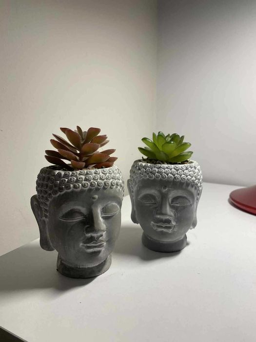 dwie figurki budda ze sztucznym kwiatkiem