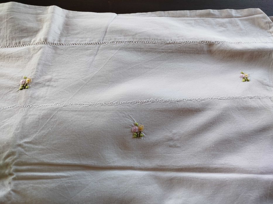 Lençol e almofada com flores bordadas a mão.