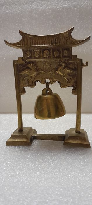 Mosiężny ozdobny dzwonek wiszący na stojaku.