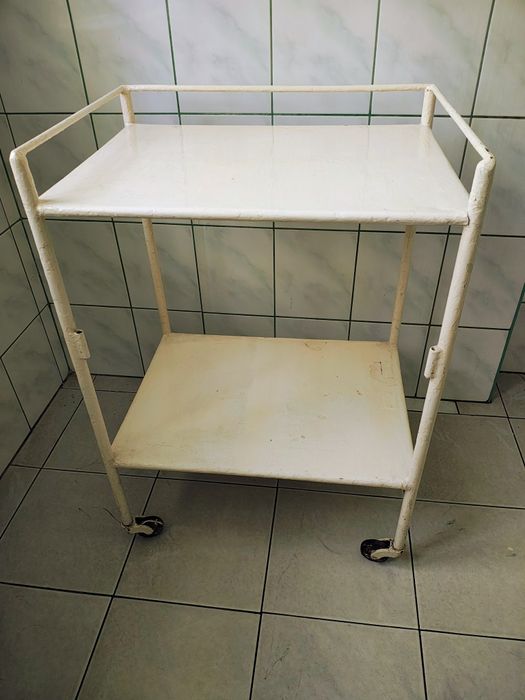 Metalowy stolik lekarski na kółkach.