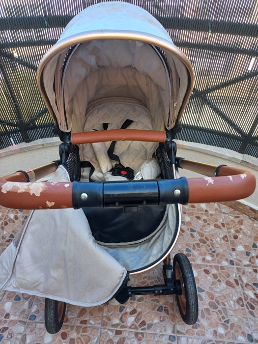 Carrinho de bebé com mmarcas de uso no puxador.
