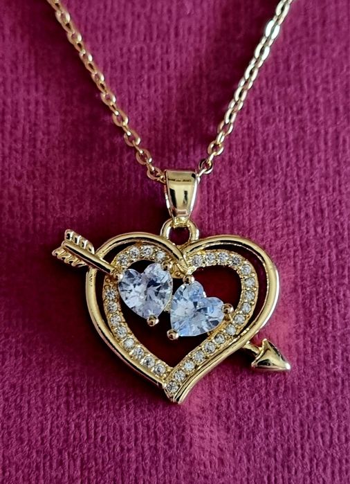 Colar dourado, em aço, com 2 corações unidos por uma flecha.